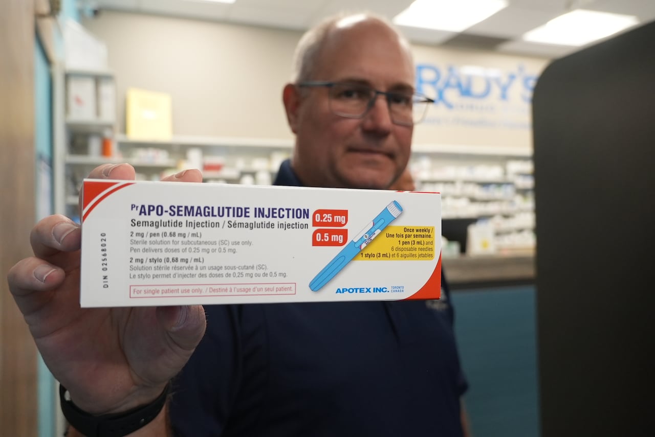 A man is blurry in the background as he holds up a box that is in focus in the front. It reads 'Apo-semaglutide Injection' and it is a generic semaglutide.