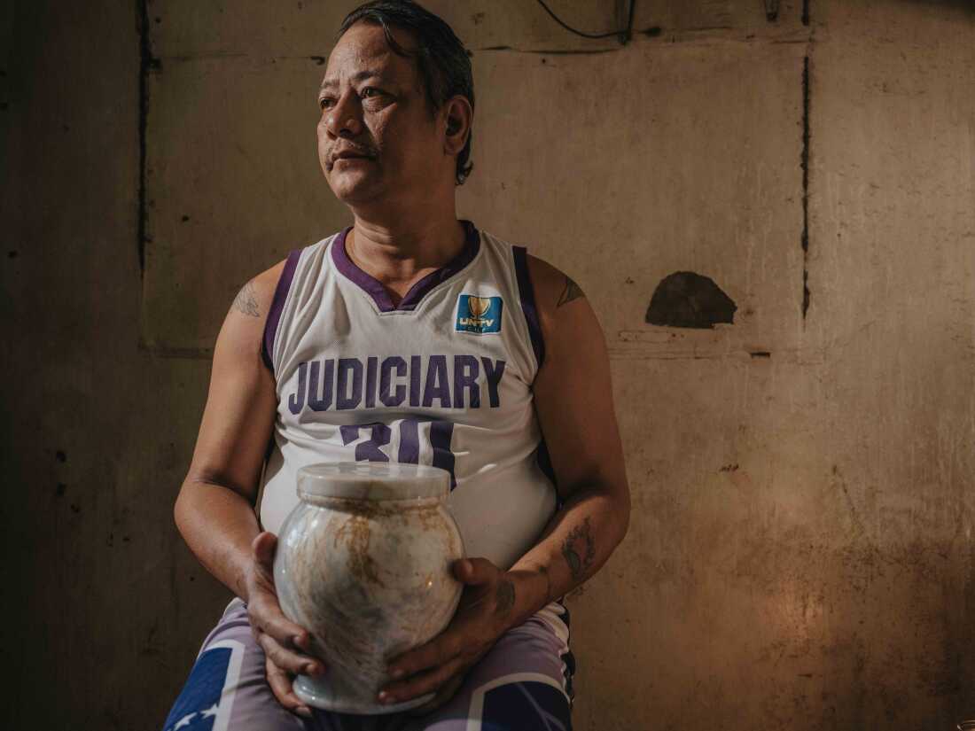 February 25, 2025. Quezon City, Philippines. Arthur R. Caballero holds the urn containing the ashes of his mother, Erma R. Caballero, in a quiet moment of remembrance. The funeral service, provided free of charge by the Mayor of Quezon City, is part of a local initiative aimed at supporting families who cannot afford funeral expenses. This program offers dignified services to those in need, ensuring that no one is denied a proper farewell for their loved ones due to financial hardship. Photo Credit: Juan Arredondo.