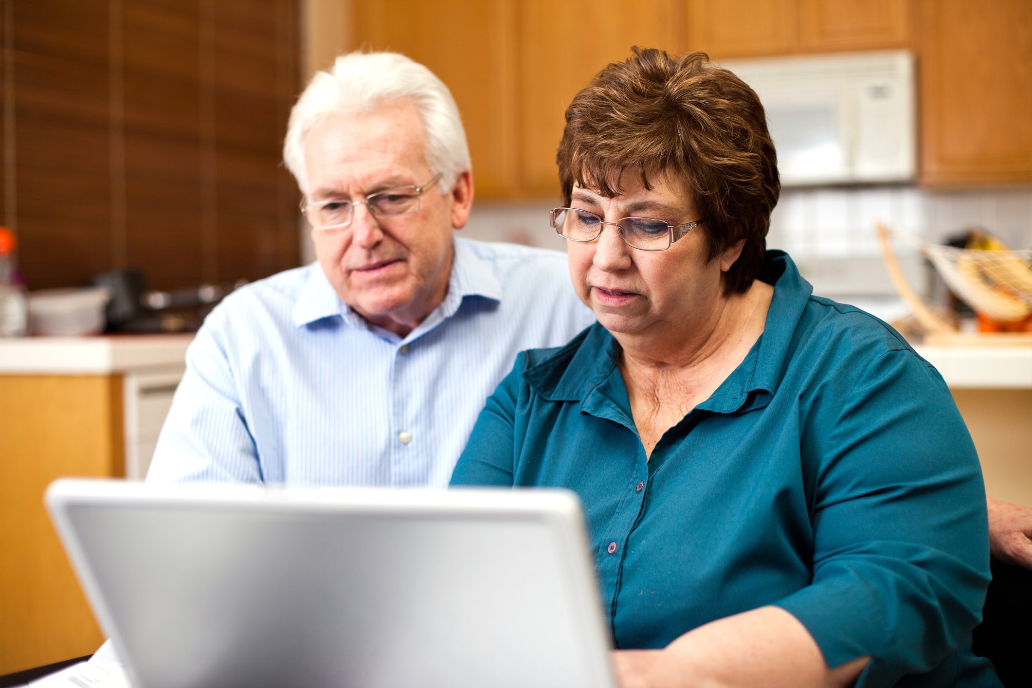 Two people at a laptop with serious expressions.