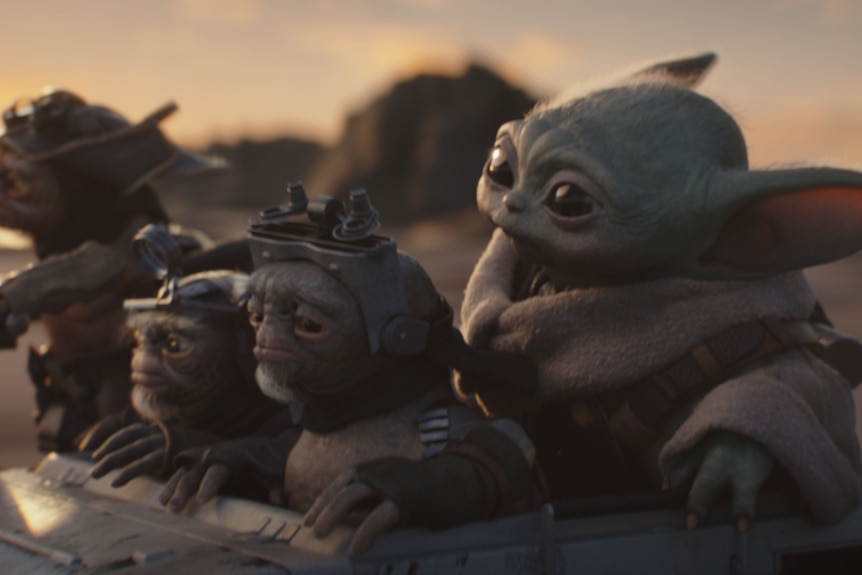 Four small creatures ride in a cart in the desert