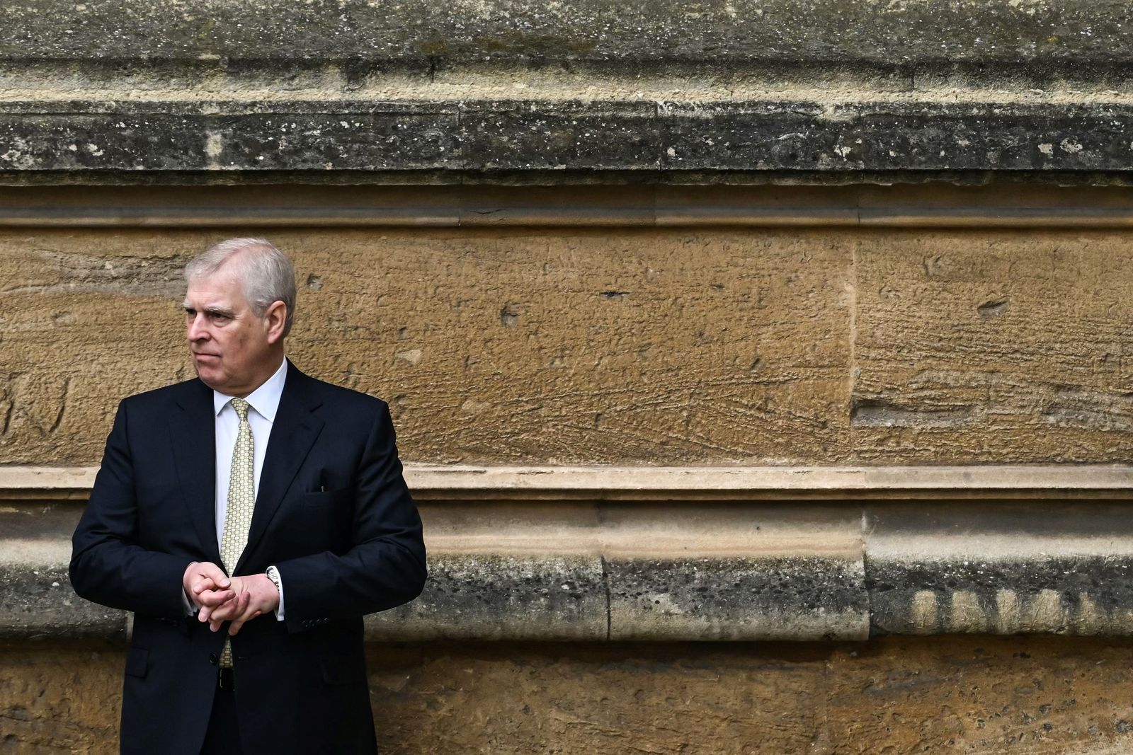 Image may contain Adult Person Clothing Coat Rock Architecture Building Wall Jacket Sitting and Formal Wear
