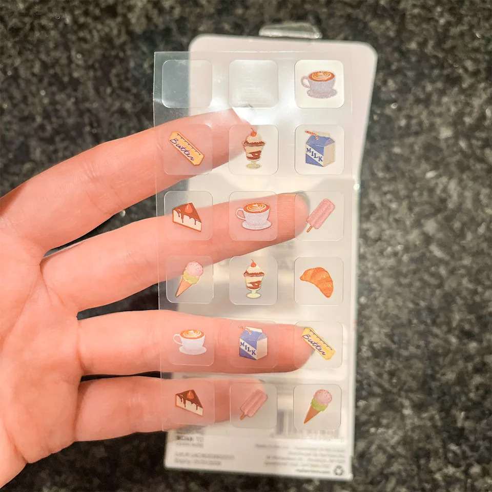 Sheet of food-themed stickers held between fingers.
