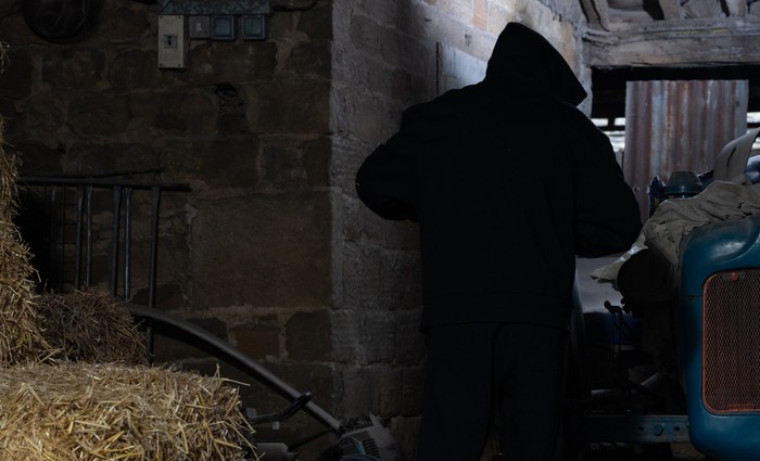 A hooded figure stands in a barn in Emmerdale