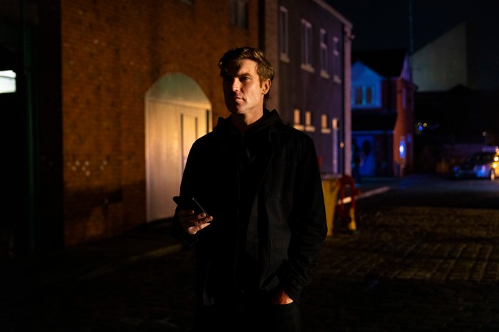 27_04_coro_todd_taxi_theo_02 Theo stands in a darkened street in Coronation Street