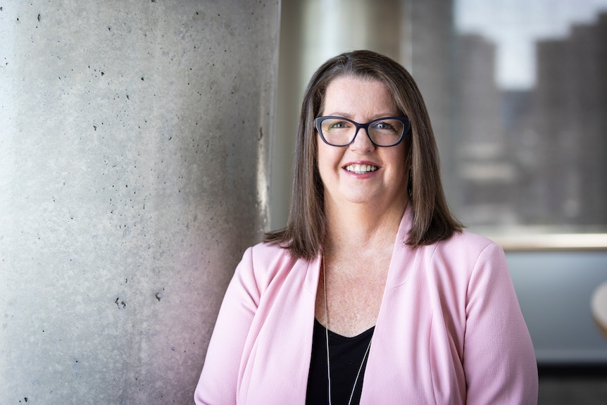 Woman with brown hair and glasses smiles at camera.