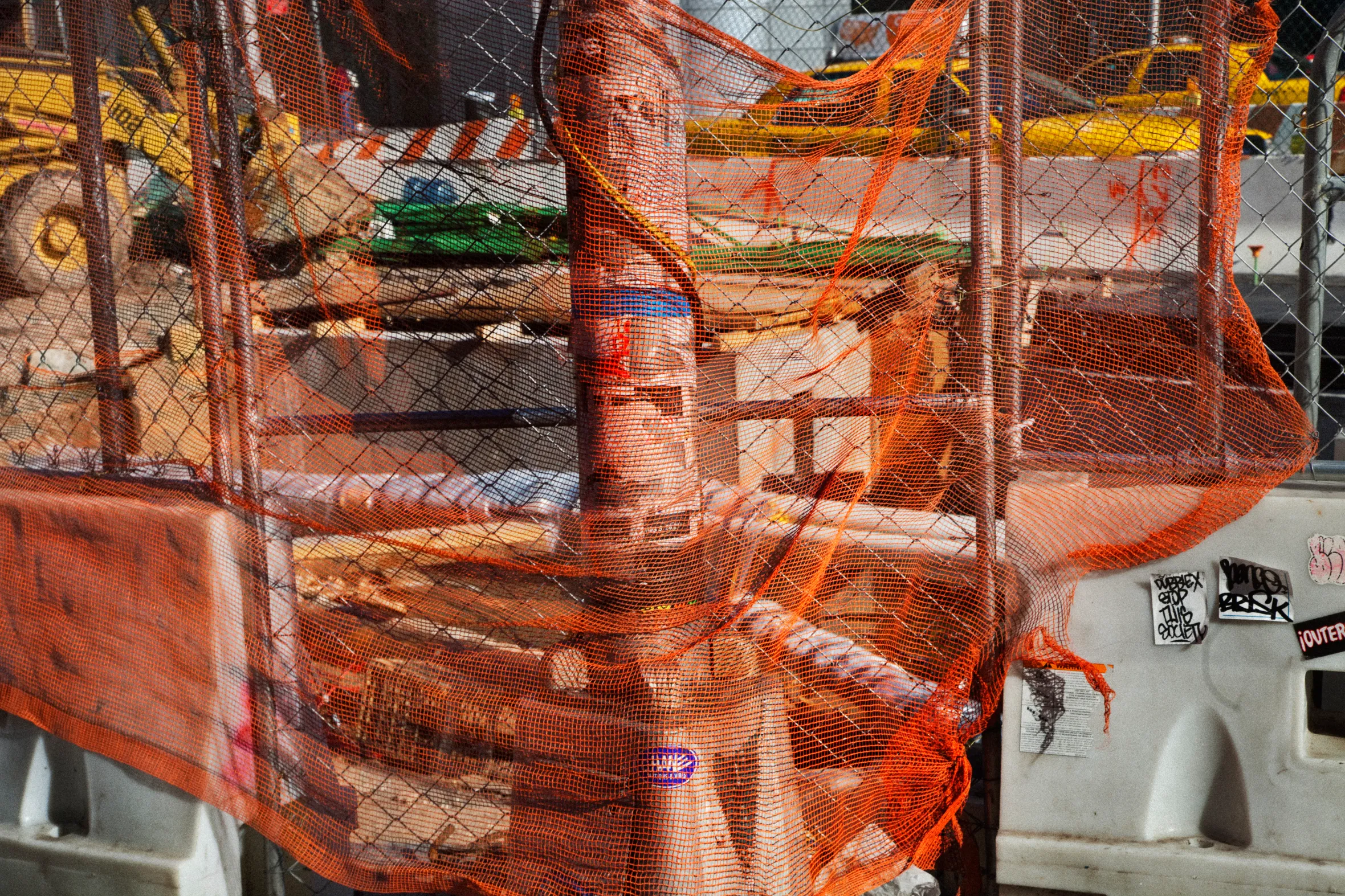 Orange construction safety netting covers a chain-link fence.