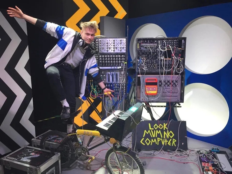 Look Mum No Computer balances on the saddle of his synthesiser bicycle