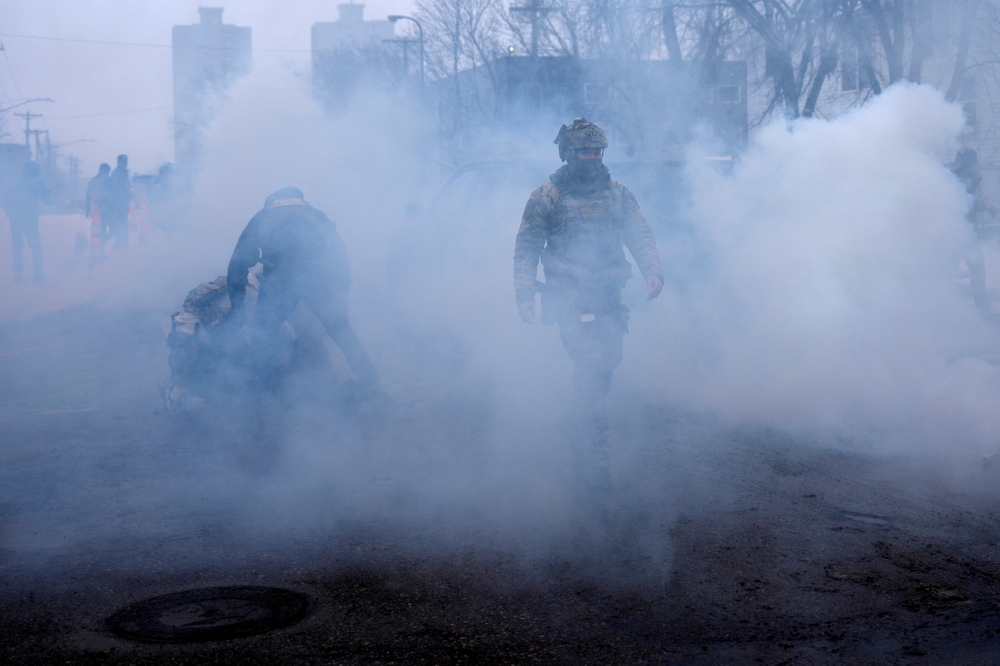 A federal agent walks as others hold a person down while being surrounded by tear gas used to deter protesters, as immigration enforcement continues after a US Immigration and Customs Enforcement (ICE) agent fatally shot Renee Nicole Good on January 7 during an immigration raid, in Minneapolis, Minnesota January 21, 2026. — Reuters pic