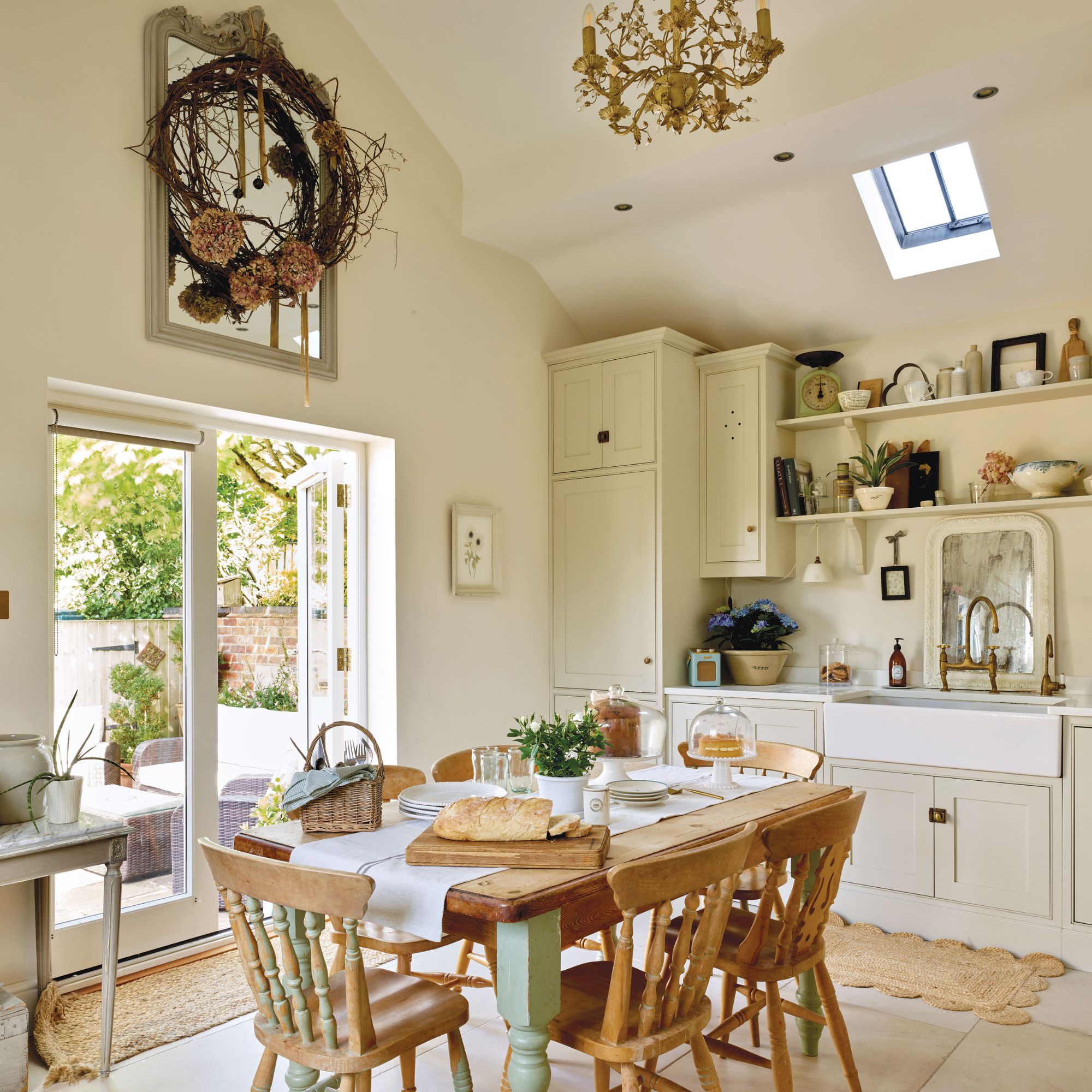 Cottage kitchen diner with wooden table, cream units, jute rug and gold chandelier
