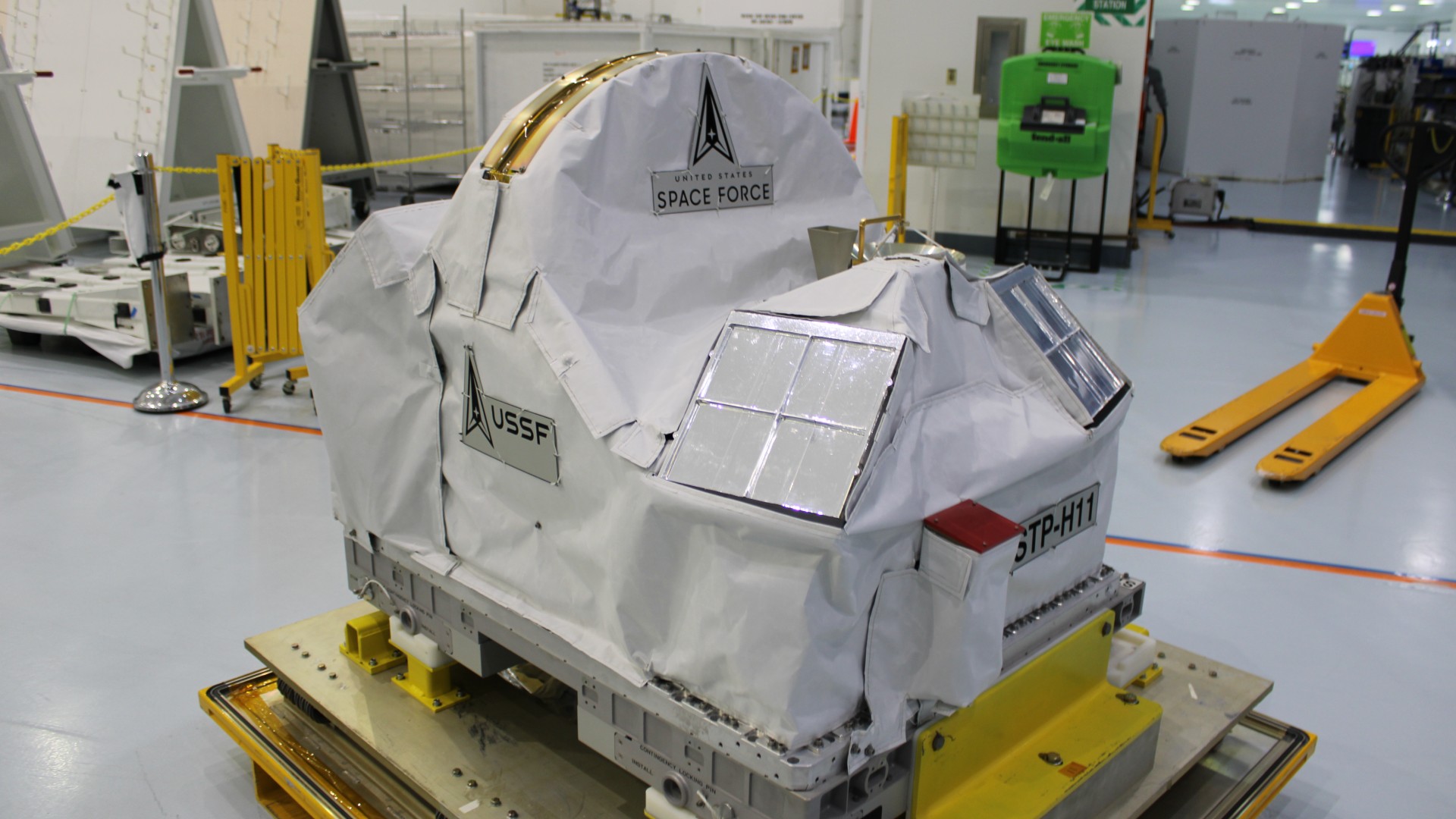 a white rectangular box-like structure on the outside of a large white cylinder above earth
