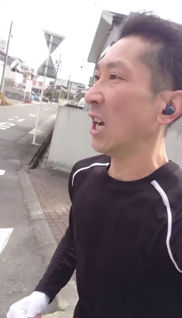 Japanese YouTuber running outdoors wearing earbuds and athletic gear during Saitama routine Japanese YouTuber running outdoors wearing earbuds and athletic gear during Saitama routine