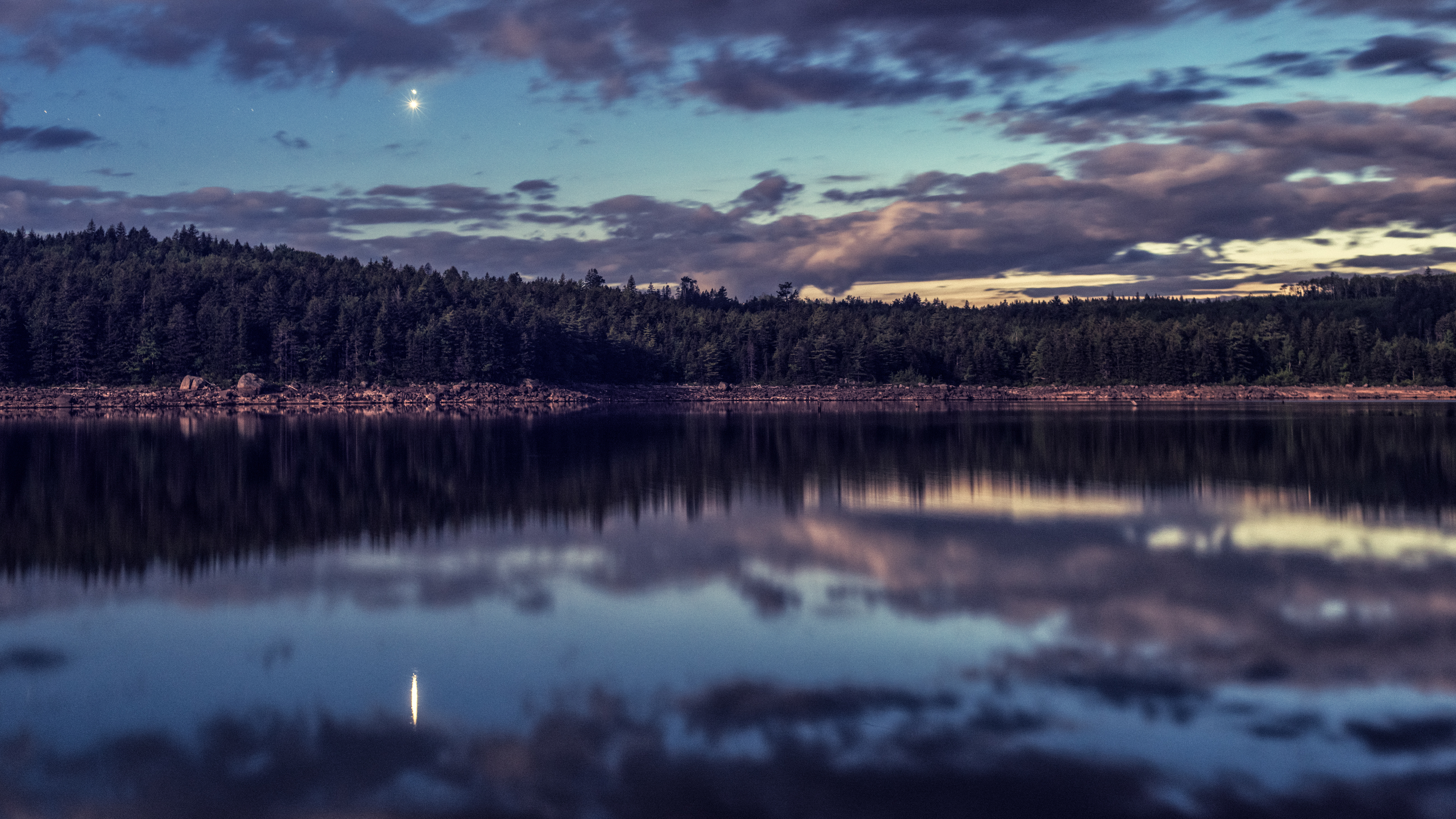 Bright planets Venus and Jupiter unite in Western skies over a very still lake illuminated by the rising Moon. Long exposure.
