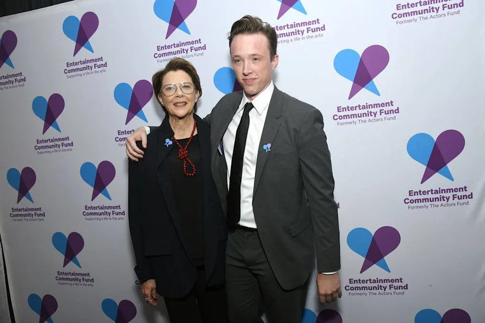 Annette Bening and Benjamin Beatty at The Entertainment Community Fund Gala in 2025. Annette wears a black top and suit with a red knot necklace, son Ben wears a grey suit, black tie and white shirt.