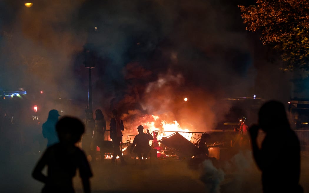 PSG supporters stand near a barricade fire in the street near the Arc de Triomphe after the club won the UEFA Champions League final between Paris Saint-Germain (PSG) and Arsenal FC played in Budapest, in Paris on May 30, 2026. (Photo by Kenzo TRIBOUILLARD / AFP)