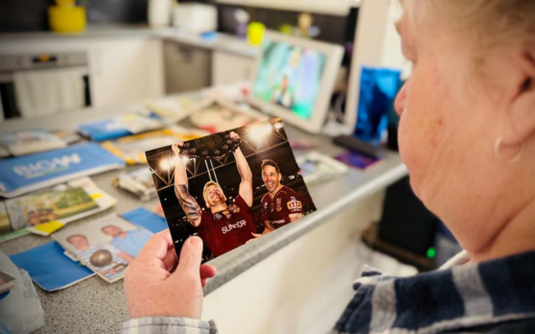 Debbie Munster holds a photo of son, Cameron, celebrating a Queensland victory.