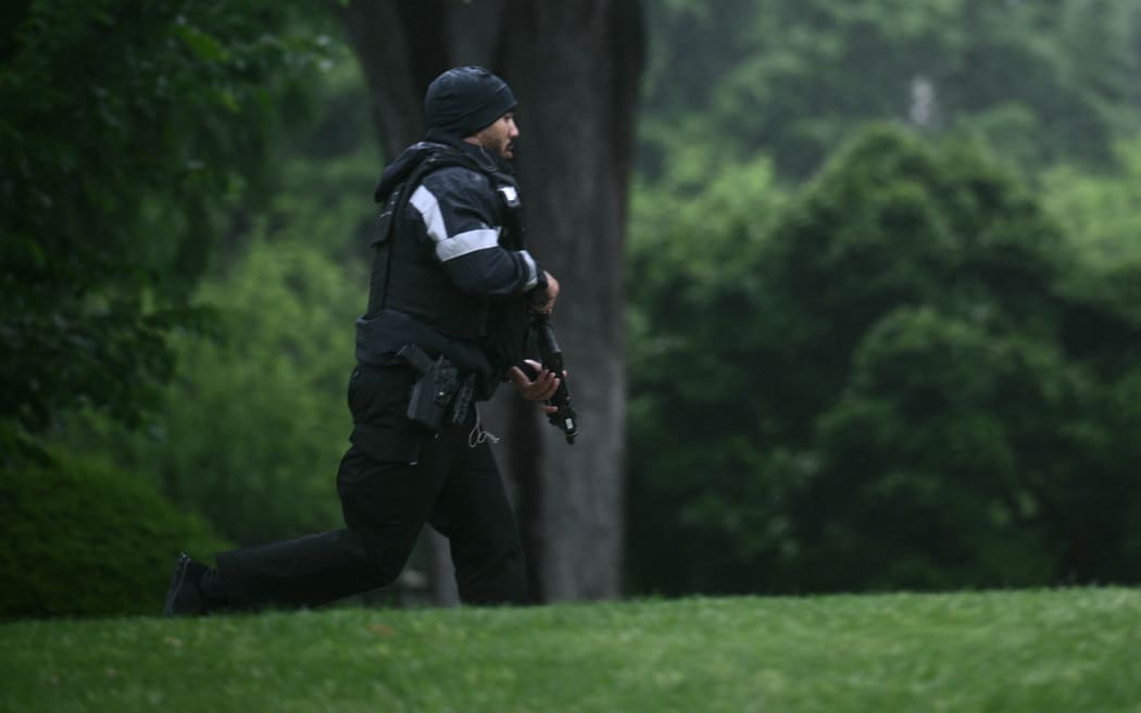 An armed Secret Service agent reacts at the White House in Washington, DC, after gunshots were apparently heard on May 23, 2026. (Photo by Brendan SMIALOWSKI / AFP)