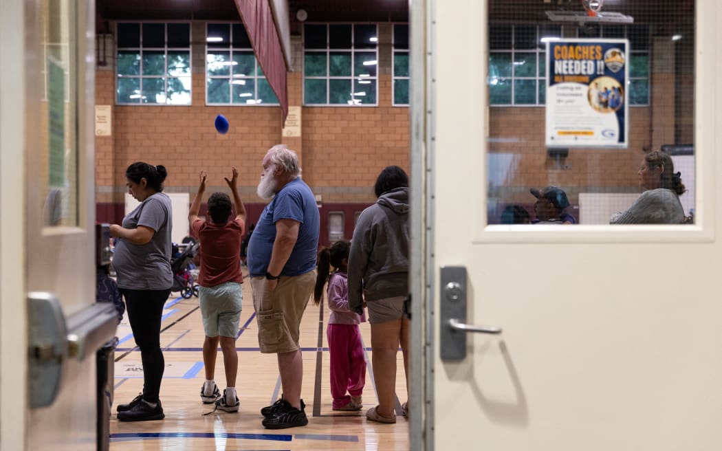 (FILES) (FILES) Evacuees wait in line for food after a chemical leak from a large storage tank threatened residents in Garden Grove, California on May 22, 2026. Tens of thousands of people were ordered to leave their homes in California on May 22, after a huge chemical tank began leaking, with warnings it might blow up, sending toxic fumes over a heavily populated area. (Photo by Blake Fagan / AFP)