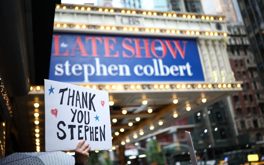 People hold signs supporting Stephen Colbert outside the Ed Sullivan Theater ahead of the taping of the final episode of the 