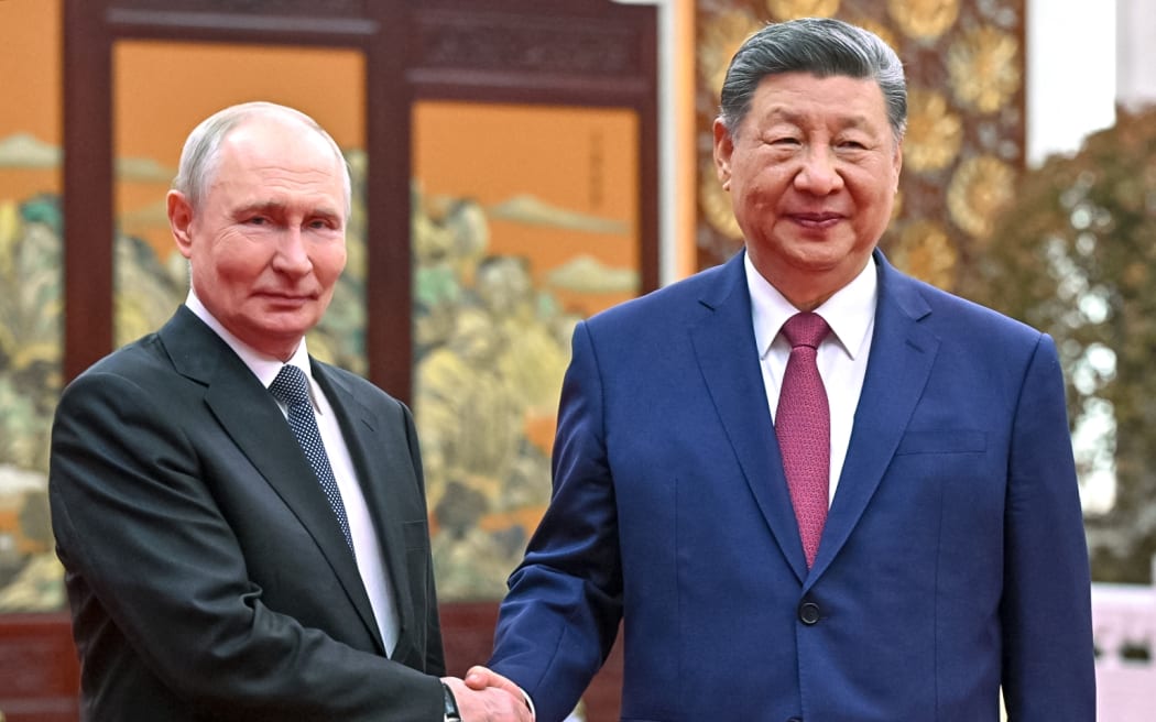 In this pool photograph distributed by the Russian state agency Sputnik, Russia's President Vladimir Putin and China's President Xi Jinping hold a tea chat in Beijing on May 20, 2026.