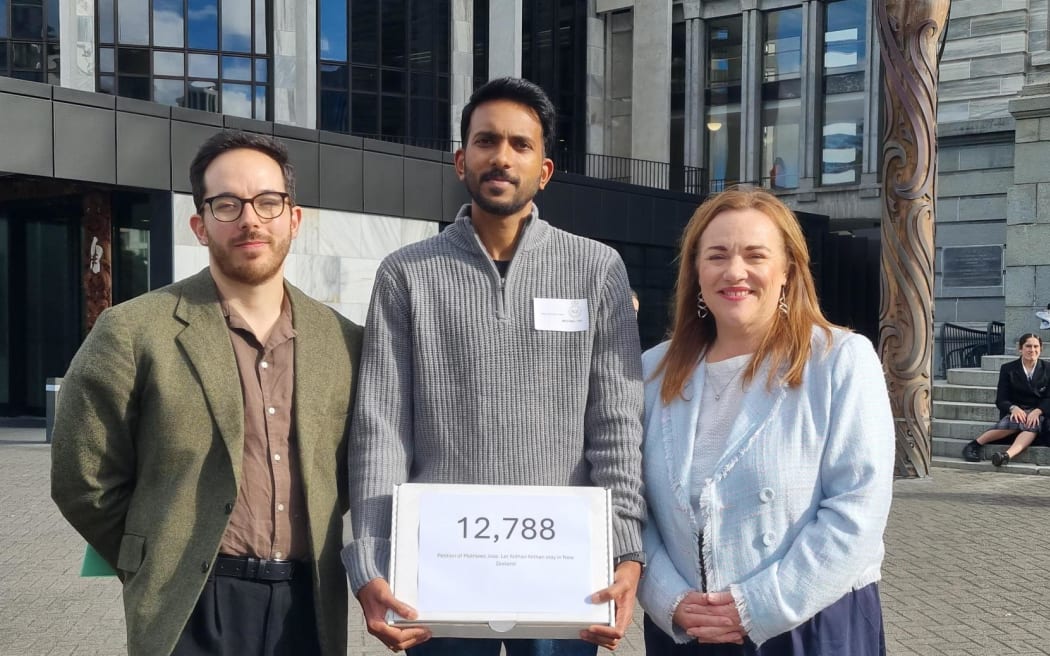 MPs Ricardo Menéndez March, left and Rachel Boyack, right, with Nithin Mankeel, whose five-year-old son is facing deportation. RNZ Giles Dexter.