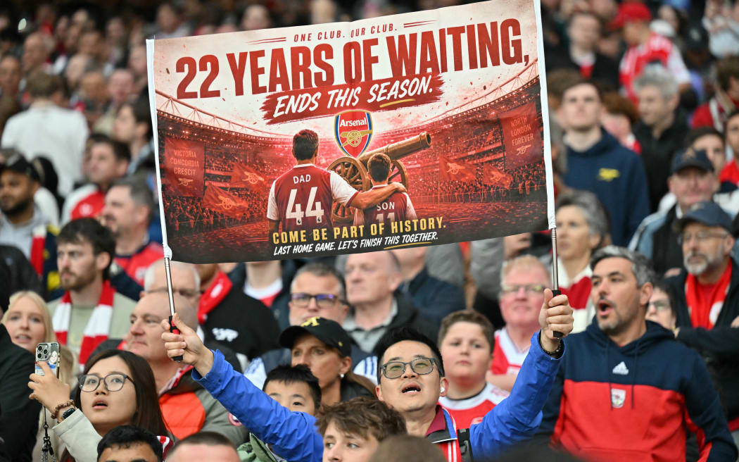 A hopeful Arsenal fan holds up a banner reading 22 years of waiting ends this season, during the English Premier League football match between Arsenal and Burnley at the Emirates Stadium in London on May 18, 2026. (Photo by Glyn KIRK / AFP) / RESTRICTED TO EDITORIAL USE. No use with unauthorized audio, video, data, fixture lists, club/league logos or 'live' services. Online in-match use limited to 120 images. An additional 40 images may be used in extra time. No video emulation. Social media in-match use limited to 120 images. An additional 40 images may be used in extra time. No use in betting publications, games or single club/league/player publications. /