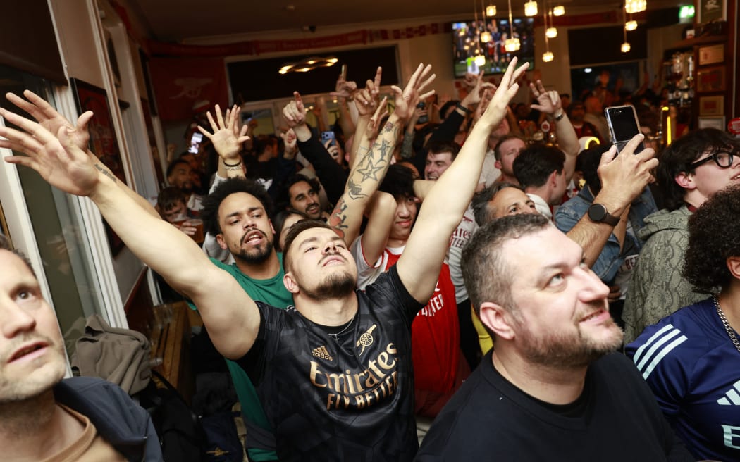 Arsenal fans cheer their team on as they watch the final minutes of the English Premier League football match between Bournemouth and  Manchester City, from inside the Tollington Arms pub near the Emirates Stadium in London.
