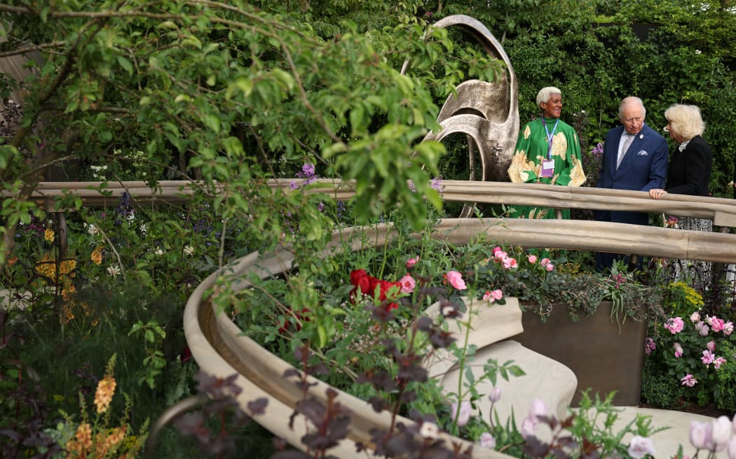 Britain's King Charles III and Britain's Queen Camilla talk with designer Arit Anderson as they view the Parkinson's UK – A Garden for Every Parkinson's Journey garden, at the 2026 RHS Chelsea Flower Show in London on May 18, 2026. (Photo by Adrian DENNIS / POOL / AFP)