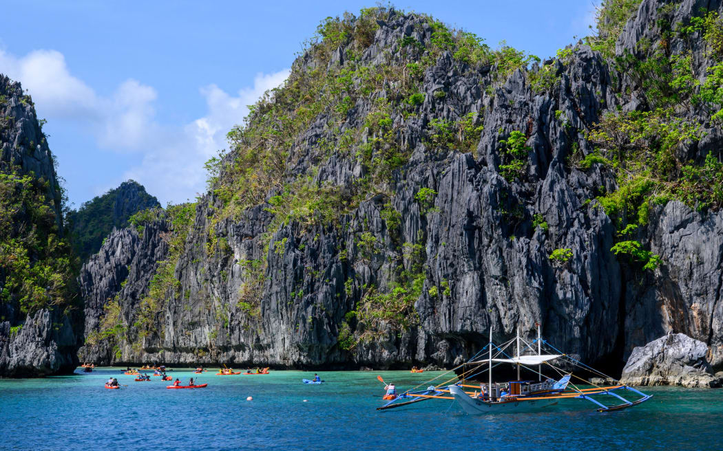 This photograph taken on December 2, 2025 shows tourists kayaking in the Big Lagoon off the coast of El Nido town in Palawan province in the Philippines. (Photo by Mladen ANTONOV / AFP)