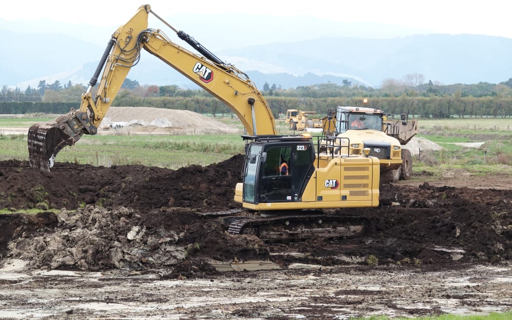 A digger removes peat from the wetland area.