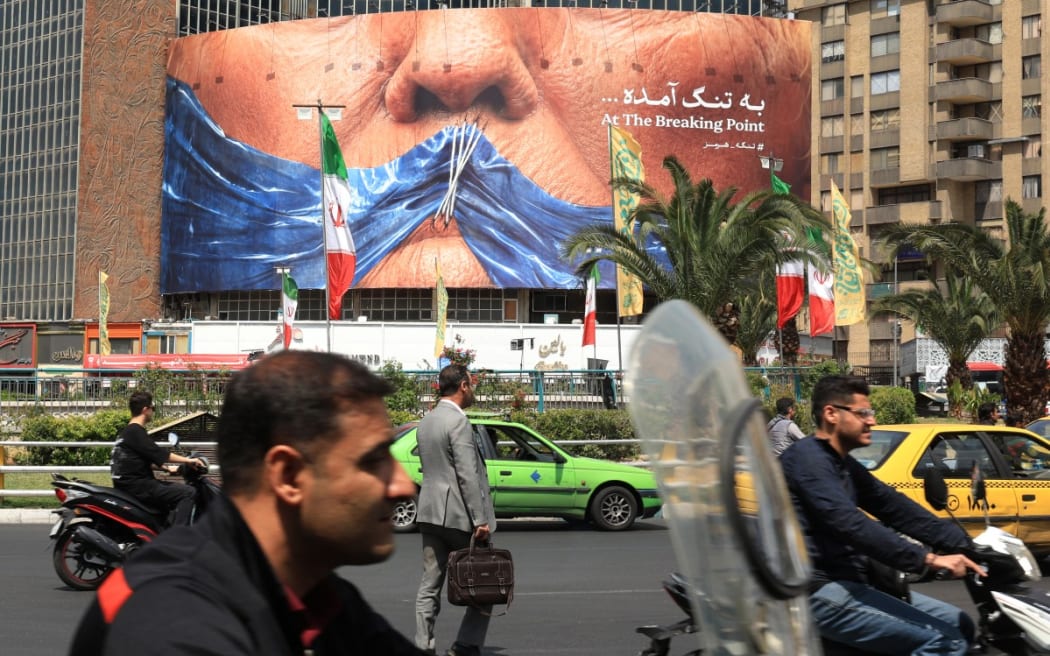 Commuters make their way past an anti-US billboard depicting US President Donald Trump and the Strait of Hormuz, in Tehran on 2 May, 2026.