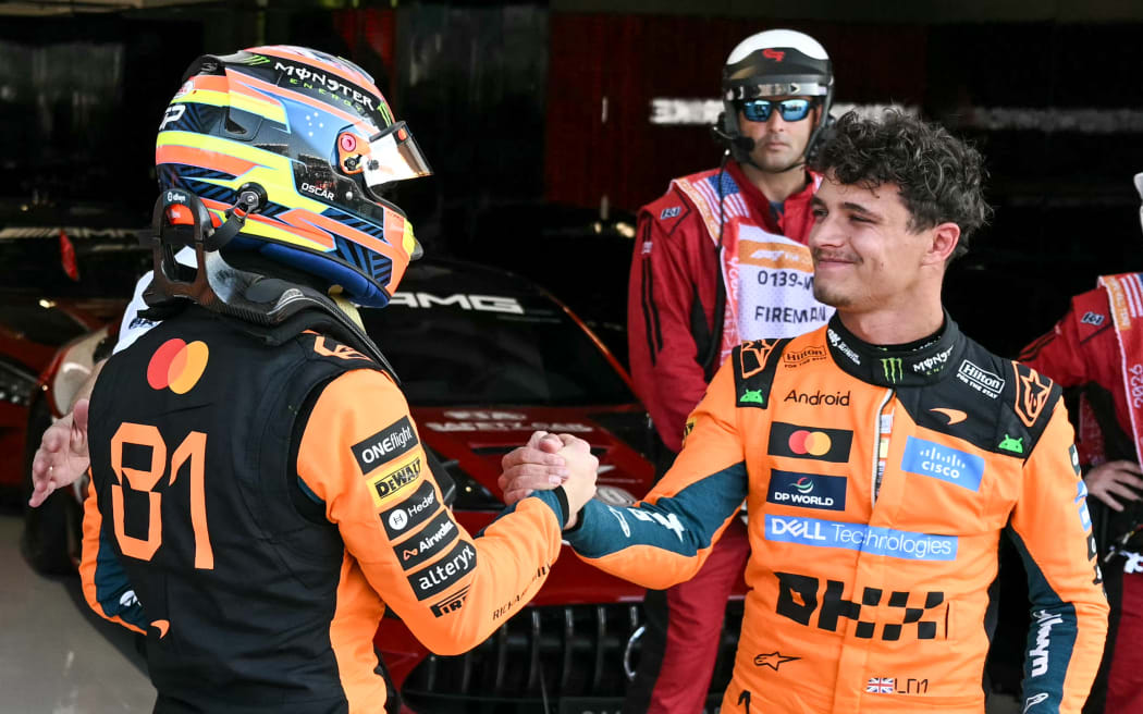 McLaren's Australian driver Oscar Piastri (L) shakes hands with McLaren's British driver Lando Norris.