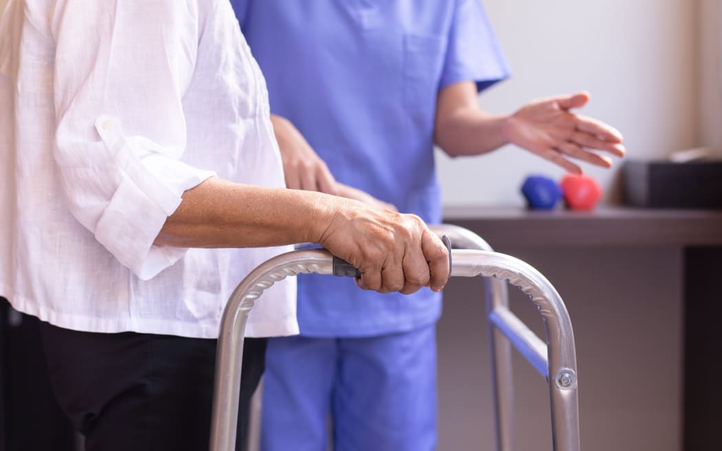 Nurse helping senior woman hand holding walker trying to walk,Care nursing home concept
