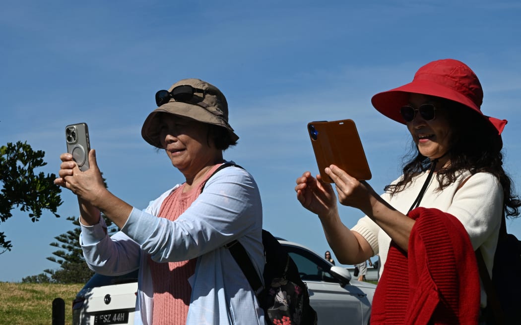 This picture taken on April 27, 2026 shows tourists taking pictures of a well-known street in Gerringong, around a two-hour drive south of Sydney. Viral posts of an Australian street dubbed the country's "most beautiful" have enticed coachloads of visitors to a picturesque seaside town -- and locals have had enough of it. (Photo by Saeed KHAN / AFP) / To go with AFP story Australia-tourism-internet by Oliver Hotham