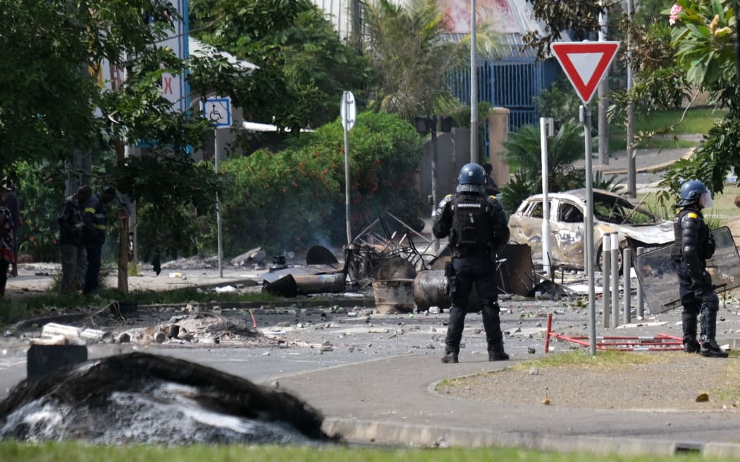French gendarme officers guard the entrance of the Vallee-du-Tir district, in Noumea on May 14, 2024, amid protests linked to a debate on a constitutional bill aimed at enlarging the electorate for upcoming elections of the overseas French territory of New Caledonia. After scenes of violence of