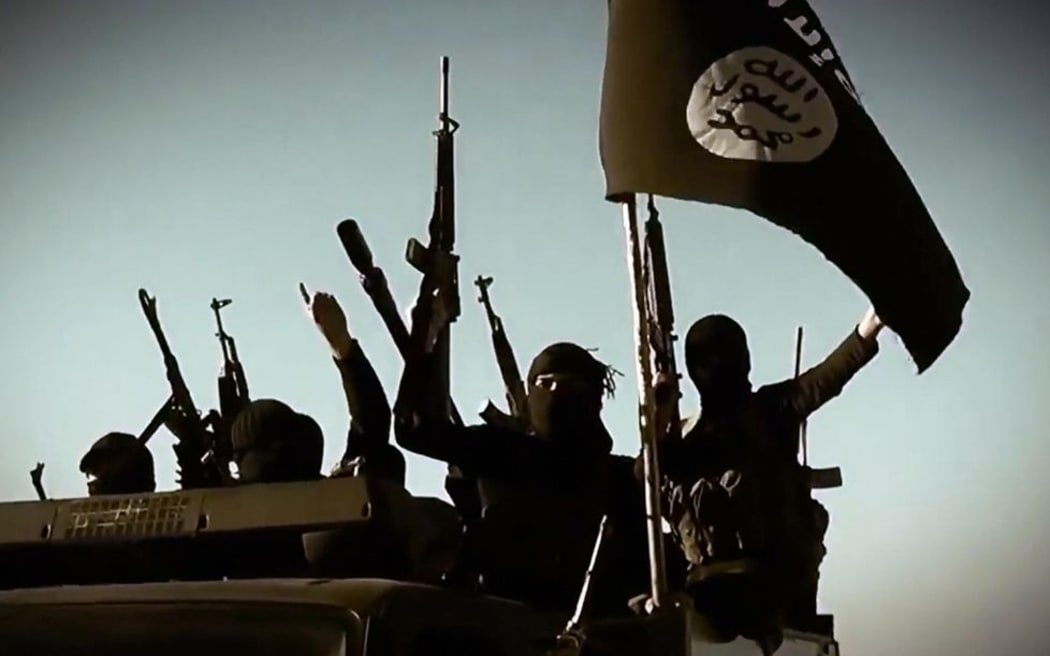 Alleged ISIL fighters raising their weapons as they stand on a vehicle mounted with the trademark Jihadists' flag at an undisclosed location in Anbar province