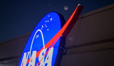 The crescent moon and Venus shine in the night sky above the NASA "Meatball" logo on the side of a building.