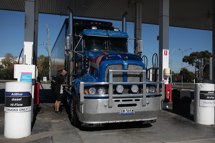 Sean Mulvaney fills up a large blue and red truck at a petrol station.