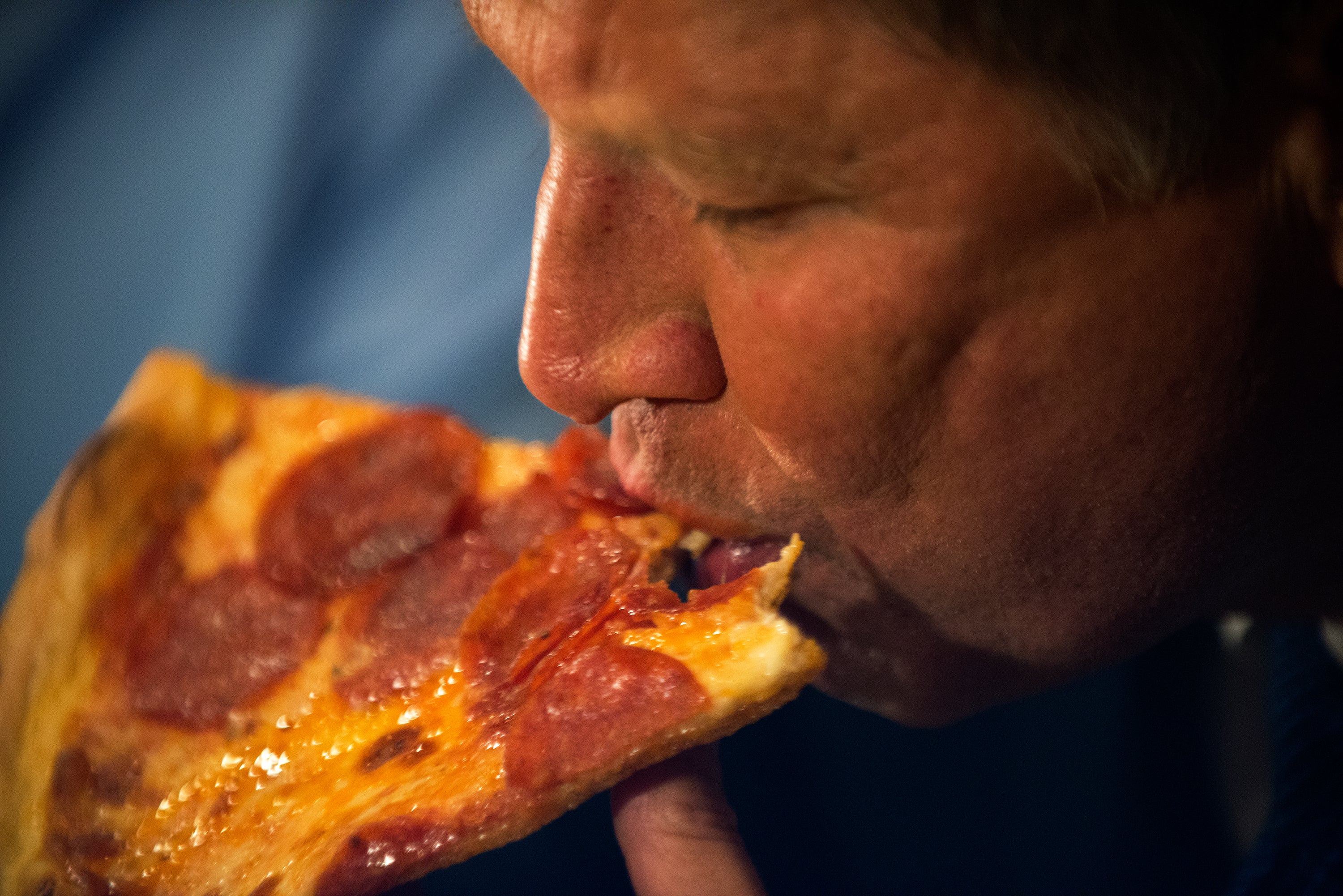 Former GOP Presidential Candidate John Kasich eats a piece of pizza at Gino's Pizzeria and Restaurant in New York City in March 2016. Pizza is one of the ultraprocessed foods most binged over the last few decades