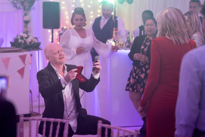 563279,TITLE:Eastenders Max Branning, on one knee, holding a ring in a box and a microphone in a scene from EastEnders