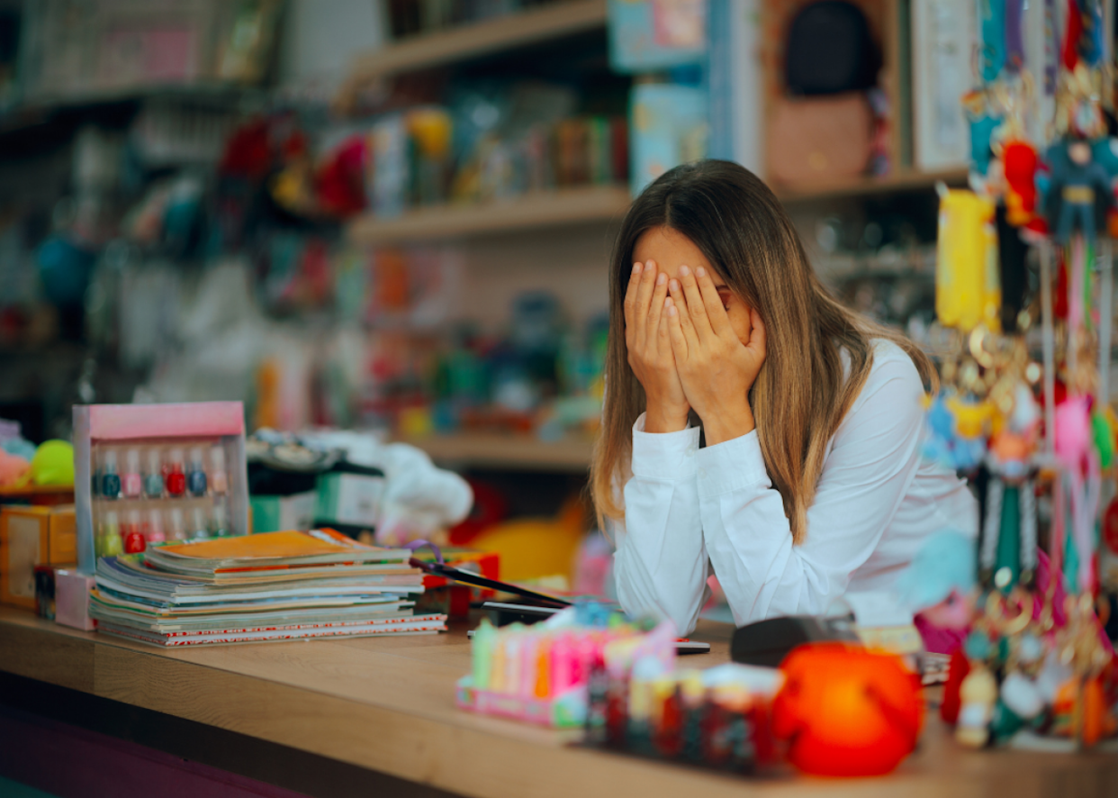 Unhappy salesperson looking exhausted behind the counter -