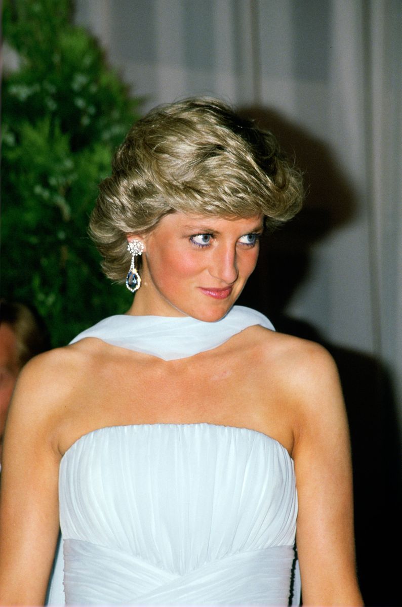 The Princess is wearing a pale blue silk chiffon strapless dress with a matching chiffon stole designed by fashion designer Catherine Walker  