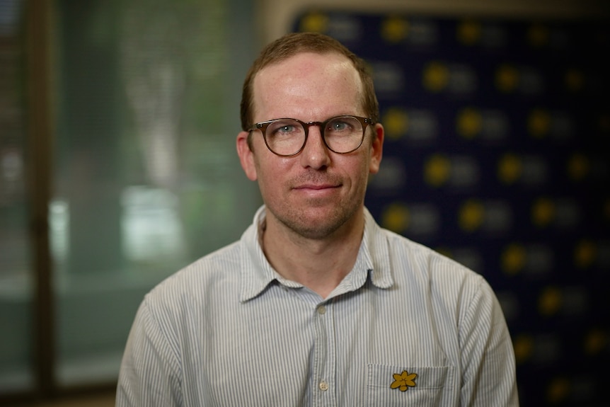 A man with round glasses stares at the camera.