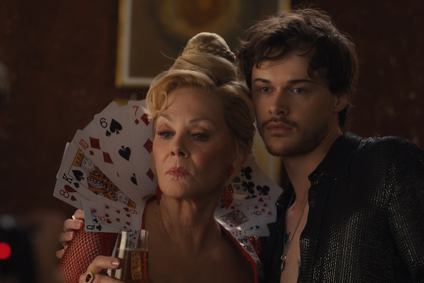 A woman and young man. The woman is surrounded by playing cards.