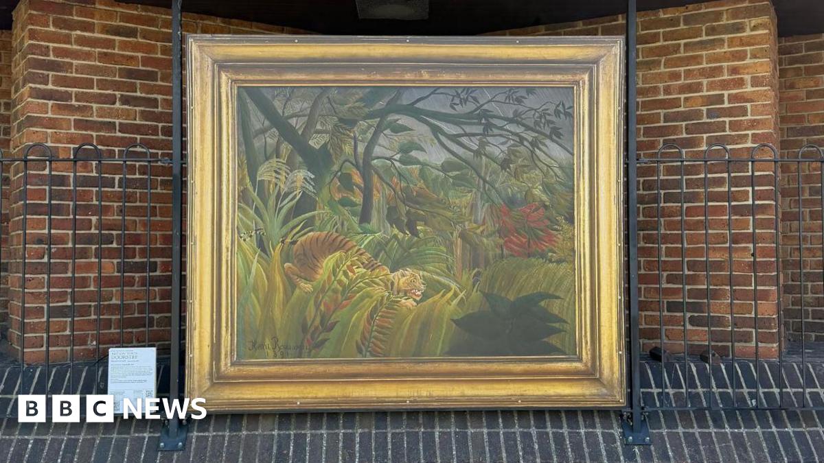 Surprised! by Henri Rousseau reproduction in a gold frame mounted on a briack wall