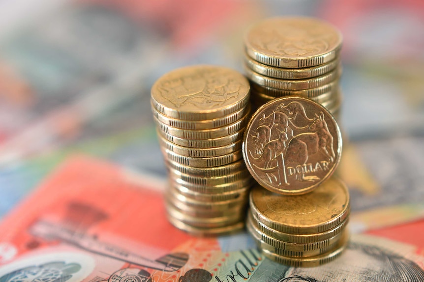 Australian dollar coins stacked up in three piles on top of twenty-dollar notes.