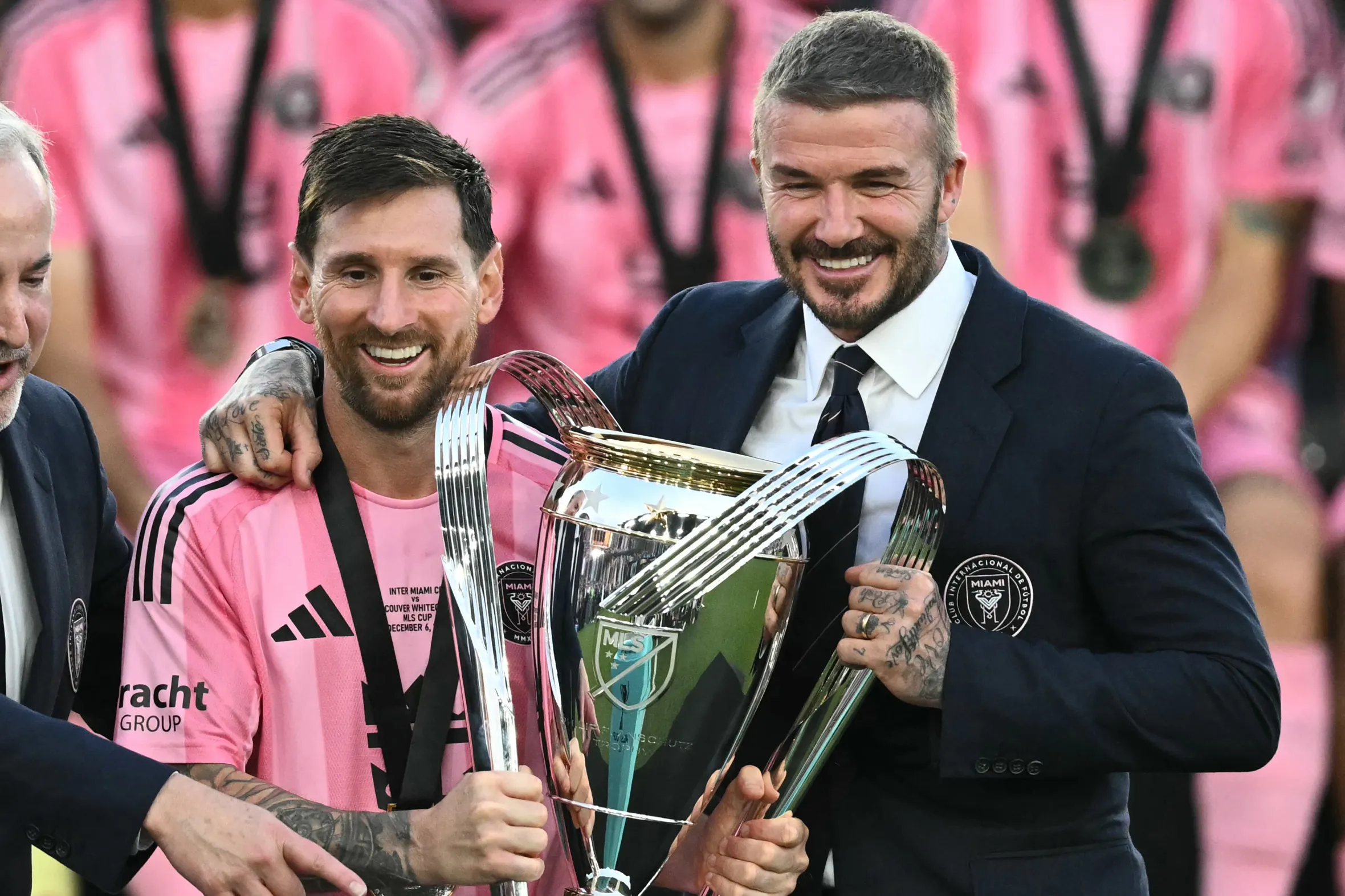 Lionel Messi and David Beckham holding the MLS Cup trophy.