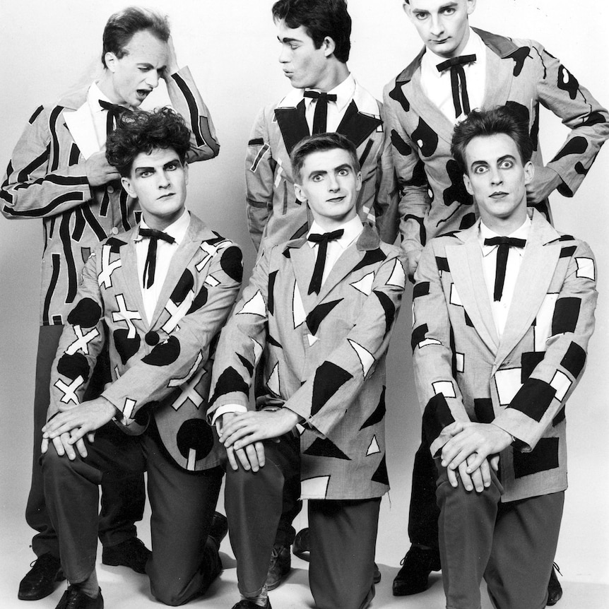 black and white photo of six split enz members wearing matching suits covered in triangles and squares