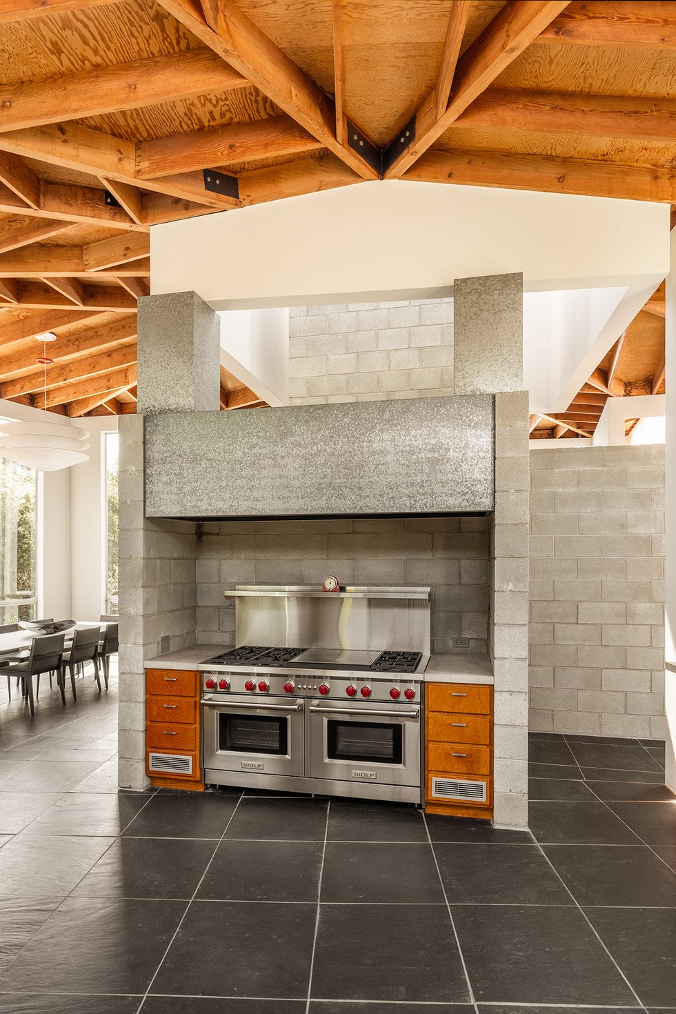 Modern kitchen featuring a large stove and concrete walls.