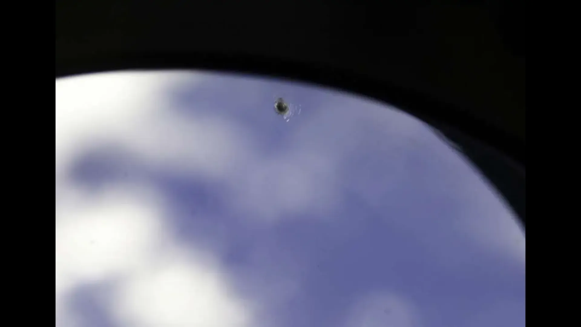 A little blob that looks like a bullet mark on a window.