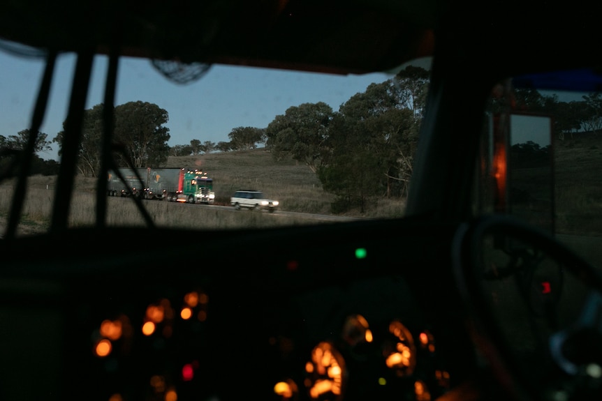 Trucks travel on the Hume Highway, as visible from inside the cab of a truck on the road.